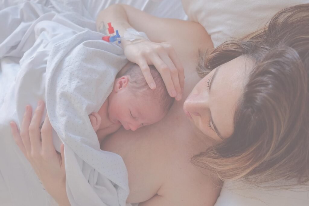 Een moeder ligt met haar pasgeboren baby huid-op-huid direct na de geboorte.