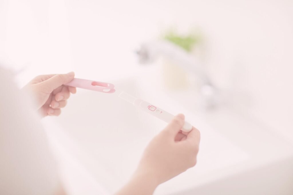 Een vrouw houdt een positieve zwangerschapstest vast boven de wastafel.