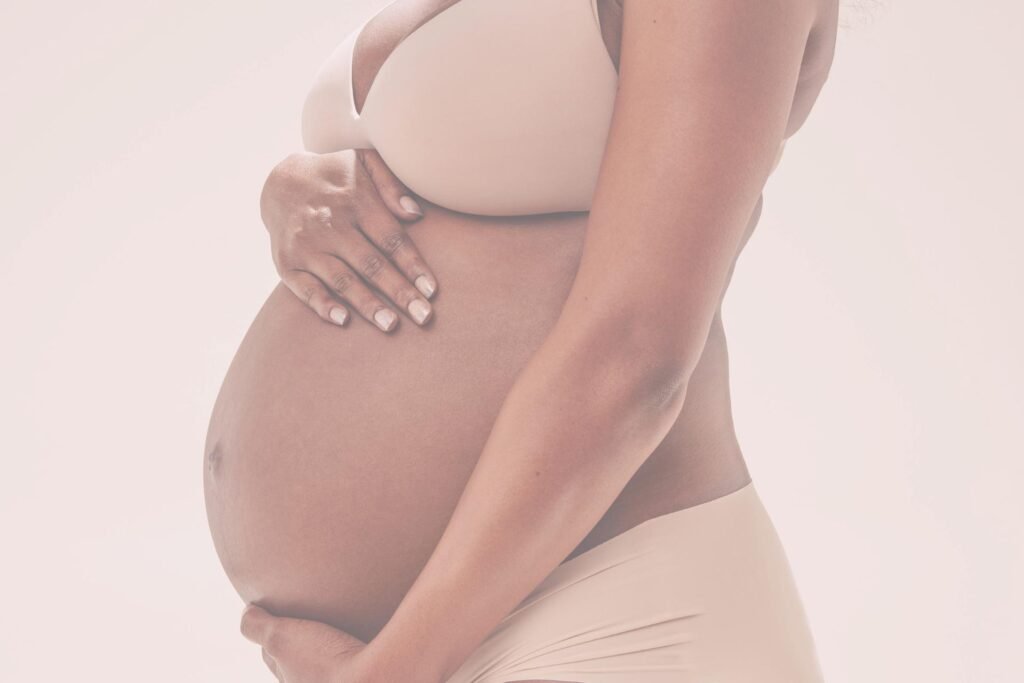 Een zwangere vrouw houdt haar handen op haar buik en toont haar groeiende lichaam.