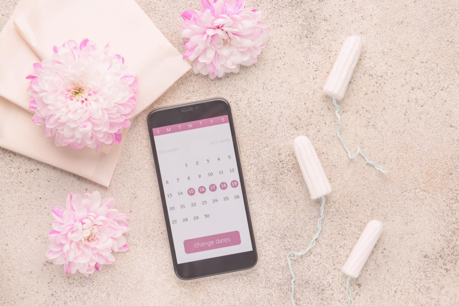 Een smartphone met cyclus-app ligt naast menstruatieproducten op een zachte, neutrale achtergrond.