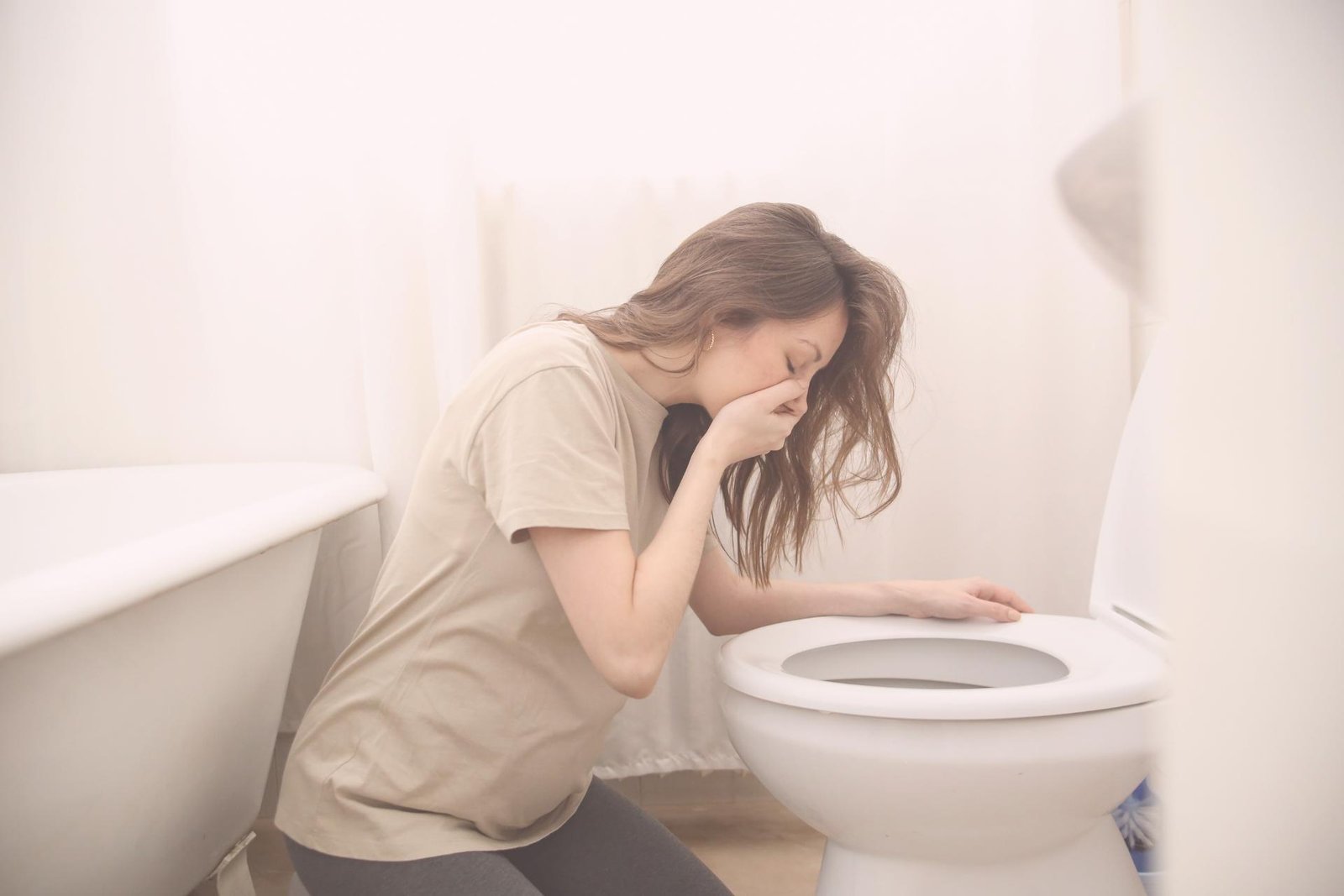 Vrouw misselijk boven toilet tijdens vroege zwangerschap