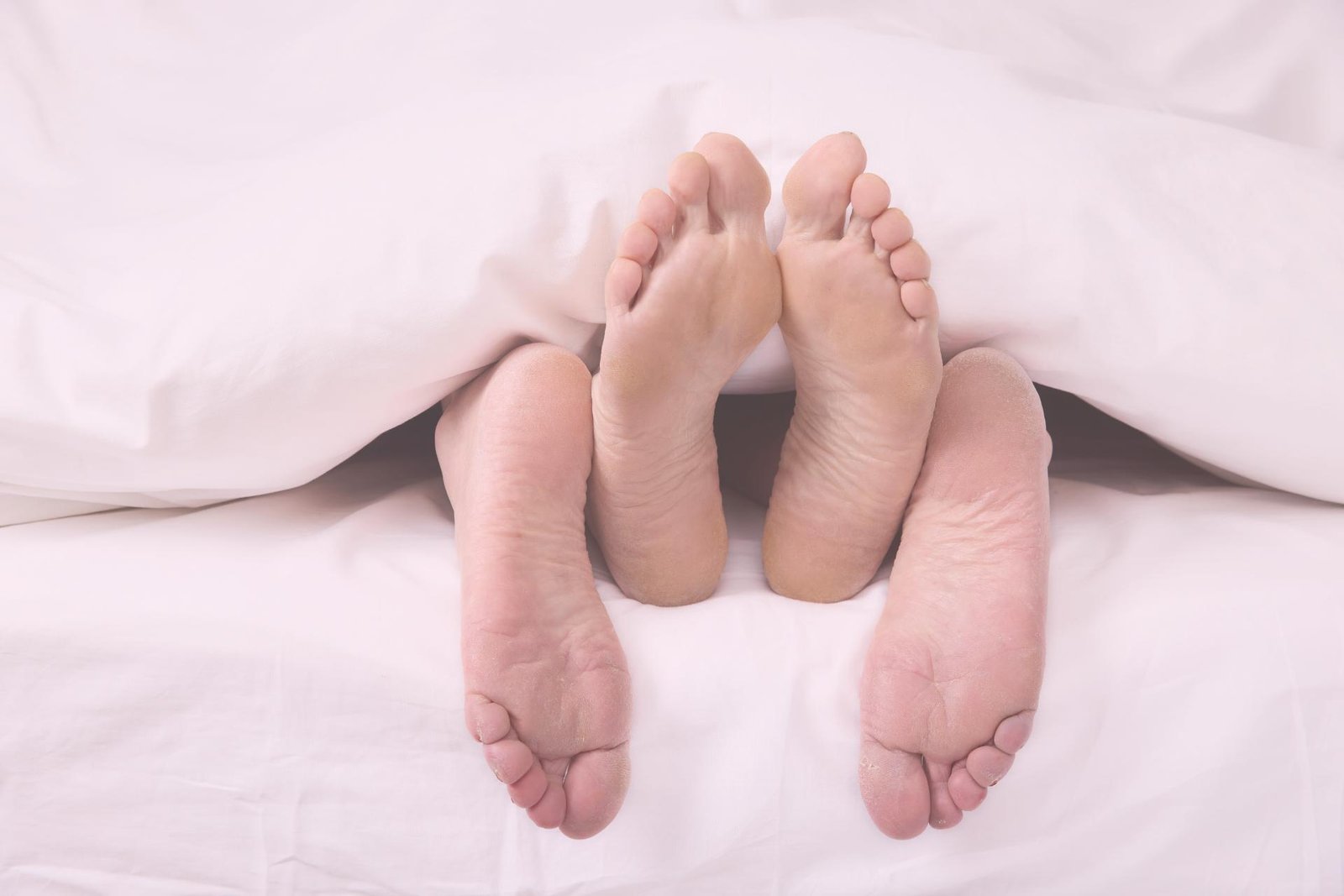 Voeten van koppel onder de lakens tijdens intiem moment